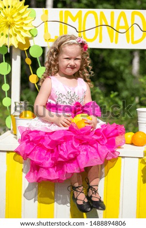Cheerful little girl drinks lemonade on the street in the park