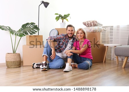 Young married couple moving in new apartment, sitting on the floor between many boxes. New home concept. Bearded man and blonde woman resting after a move-in. Background, copy space, close up.