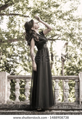 Beautiful girl in a black evening dress near the stairwell of an abandoned palace. Beautiful woman with scars. Young girl in retro style. Pretty Woman