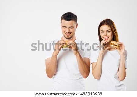 Woman and man in white t-shirts eat fast food hamburger