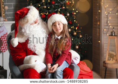 Santa Claus and little girl in room decorated for Christmas