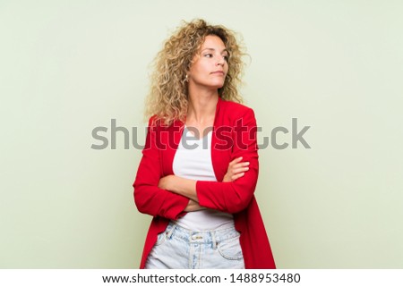 Young blonde woman with curly hair over isolated green background portrait