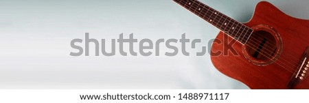 Acoustic guitar resting against a blank blue background with copy space.