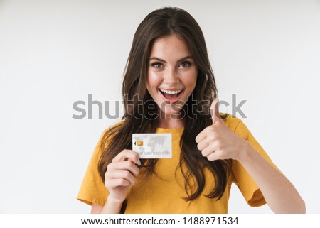 Image of gorgeous brunette woman wearing casual clothes showing thumb up and holding credit card isolated over white background