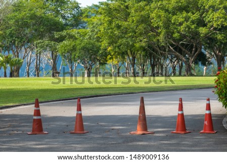 Red traffic cone on road in garden. Orange funnel use for beware car on the road in park. Cone traffic sign on road.
