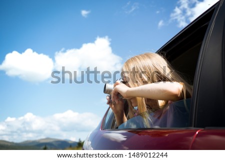 Summer Road Trip. Girl with retro camera taking pictures from the car window. 
