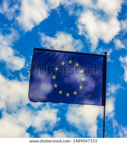 one, alone Flag of European Union / EU  hang  on facade of building, wave on wind. blue cloudy sky background. 