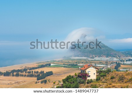 Beautiful landscape with rare atmospheric effect when fog looks like climbing over hill.