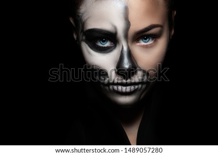 Halloween. Portrait of young beautiful girl with make-up skeleton on her face/ Closeup girl face with make-up skeleton