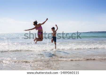 young boy and girl, brother and sister, jumping on the beach Royalty-Free Stock Photo #1489060115