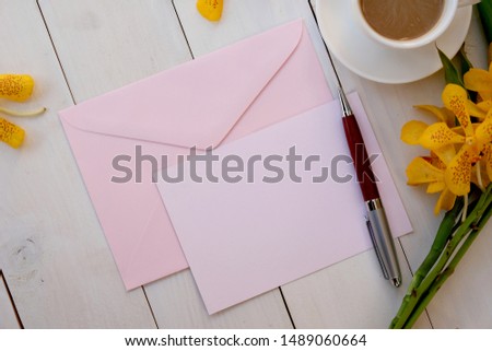 Pink paper card and an pink envelope on white wooden background, mockup. Flat lay. Top view.
