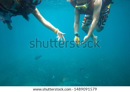 Young couple diving in deep blue sea with goggles snorkel. Scuba driving under water with fish taking photo with action camera. couple lover on vacation at tropical island on summer. travel holiday.