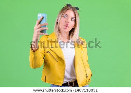 Young rebellious blonde woman making funny face and taking selfie