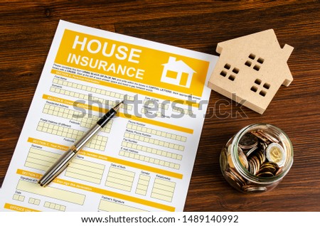 Housing marketing concept with house insurance paper, coins and pen on table, Business and insurance background concept