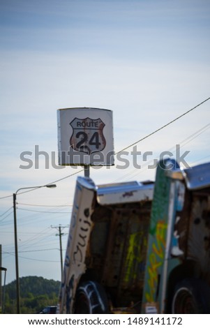 Harjunsalmi / Finland - August 25 2019: Route 24 sign on blue sky background. Old cars set standing in front. Design resembles the one in America, bu it still is in Scandinavia, Europe.