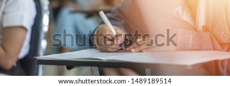 Exam at school with student's taking educational admission test in class, thinking hard, writing answer in university classroom, education and world literacy day concept Royalty-Free Stock Photo #1489189514