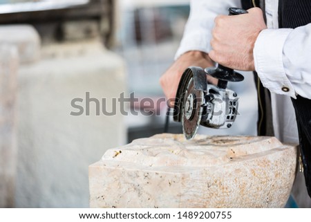 Close-up of stonemason cutting marble with angle grinder Royalty-Free Stock Photo #1489200755