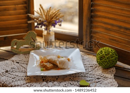 

cake on a white plate on an embroidered napkin on the windowsill