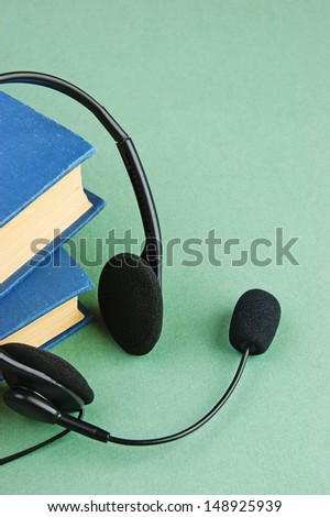 Headphones with a microphone and a stack of books on a green background