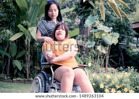 Asian fat woman are Patients sitting on a wheelchair Her hands are kinking due to a nervous system illness, hemiplegia and paralysis, With a friend to look after, to health care concept. Royalty-Free Stock Photo #1489263104