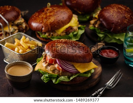 Big beef burger with onions and tomatoes. Juicy cheeseburger on a dark table.