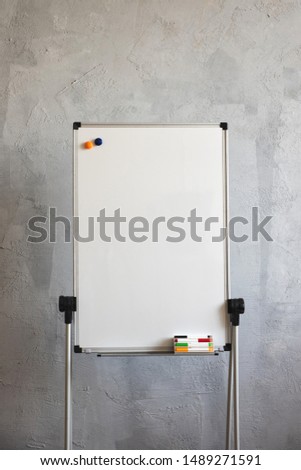 Big white board markers on grey background.  Writing board stands on the old dirty floor in the office.