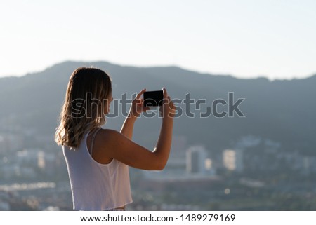 beautiful caucasian woman taking photo with mobile phone in the mountain