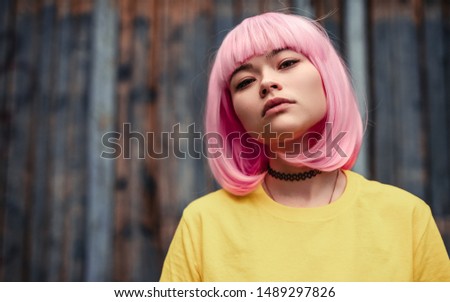 Beautiful pensive Asian woman in yellow shirt with pink hair looking at camera Royalty-Free Stock Photo #1489297826