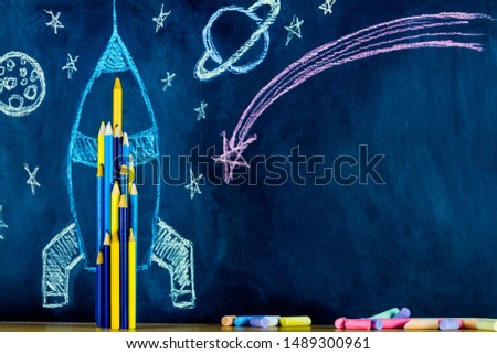 Chalk space rocket with stars and planets painted on school chalkboard with colorful chalks and pens. Back to school and ready to study concept. Chalkboard school background