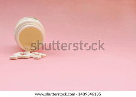 Capsule medicine background with place for text. Heap of pills pour out of the can on pink background