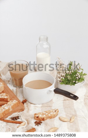 Coffee with milk, cookies, cinnamon and fruits on the tablecloth.