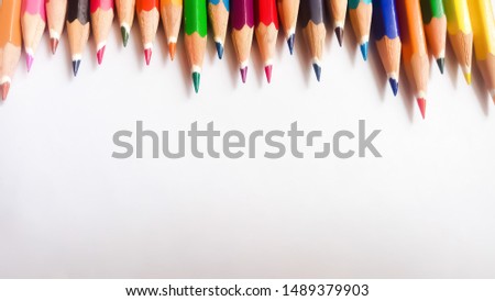 Colored pencils arranged in a row on one side. They have a soft focus and slightly blurry where the pencil colors reach the vertical ends of the frame. There is space for text below. Background image