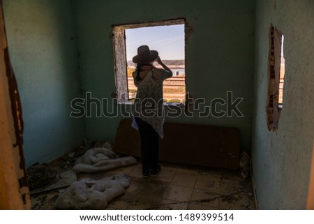 A woman takes photographs with her smartphone through the window of an abandoned house at the Rio Tajo train station near Garrovillas de Alconetar, Extremadura, Spain.