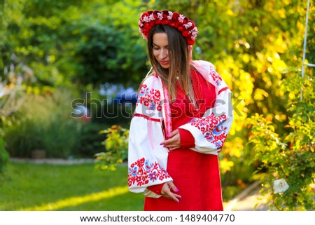 Portrait of young beautiful girl in embroidered shirt at the green sunny garden 