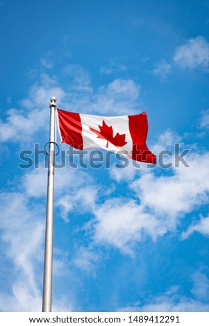 Canadian flag waving in a blue sky.