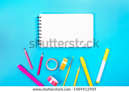 School items as a frame on blue background. Trendy colors, flat lay style. Back to school concept.