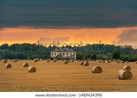 A field with straw bales after harvest during sunset.

