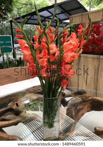 an orange flower vase on a glass table.
