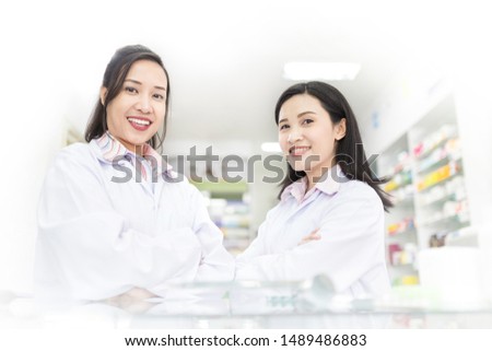 two Asian healthcare stand and cross arms in drugstore, unity and teamwork, happiness organization, asian female pharmacist feeling happy in work time