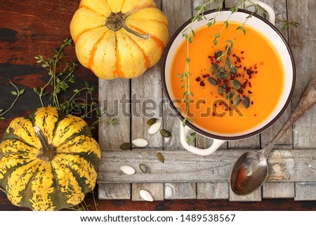Bowl of pumpkin cream soup on rustic wooden background