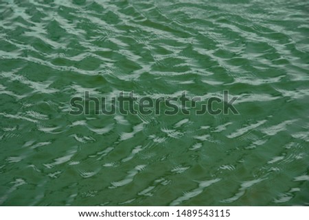 green water surface By wind.Water surface ruffled by light wind with small waves running diagonally, with reflections and graduated from light and green tones.soft focus.