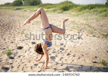 Attractive girl standing on hands in beach