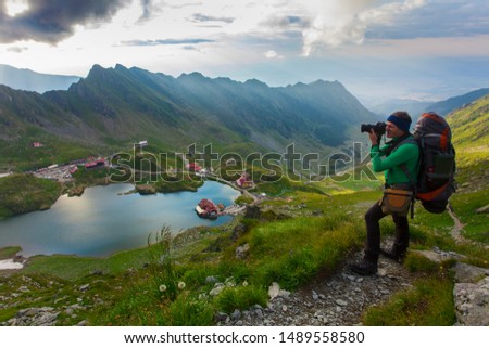 man with backpack on the mountain. photographer taking photos. Balea, Romania