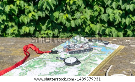 A map on a table. Opisometer,  a curvimeter,  a map measurer. Baseplate compass. Scout Compass. Green background. Scouting equipment for orientation. Orienteering. Hiking. Tourist rope.