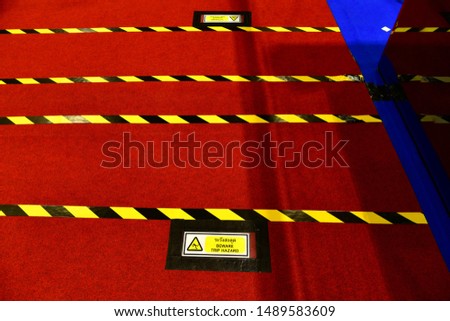 Warning sign to electric power wire cable mesh on carpet floor.