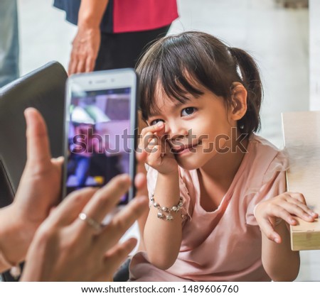 Little asian girl take a photo with a smartphone.