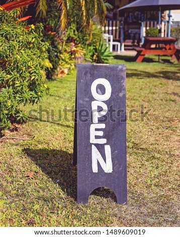 Open blackboard sign in the sunny garden of a casual country cafe