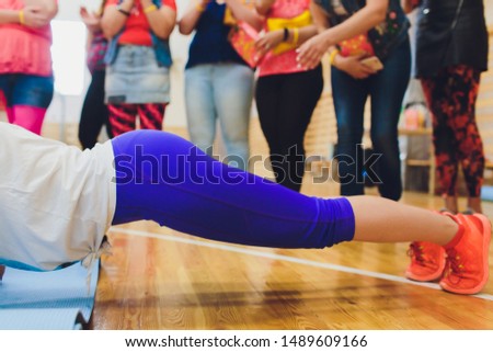 Side view of attractive young woman doing core exercise on fitness mat in the gym. Female doing press-ups in health club.