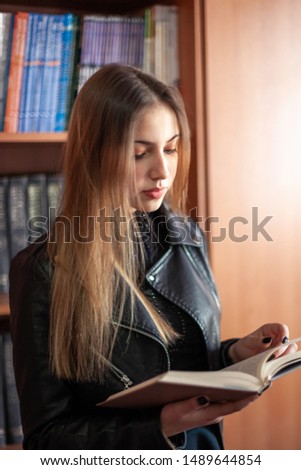 Beautiful teenager schoolgirl reading a book in the library, education.