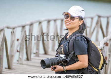 Outdoor summer lifestyle portrait of pretty young woman having happy with camera travel photo of photographer. Young woman with a camera in hand.